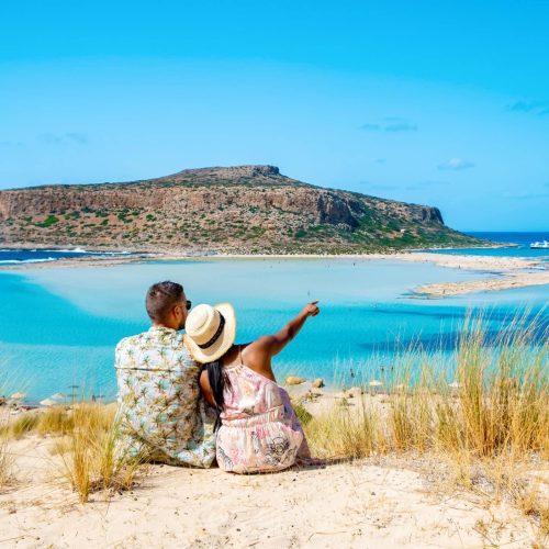 Crete Greece Balos Lagoon Crete island, Tourists relax at the crystal clear ocean of Balos Beach. a couple of men and a woman visit the beach during a vacation in Greece on a sunny day