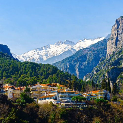 Beautiful view of the mountains of Olympus from an observation deck in the center of Litochoro. High rocky green mountains and snow-capped peaks. A small cozy village in the mountains.