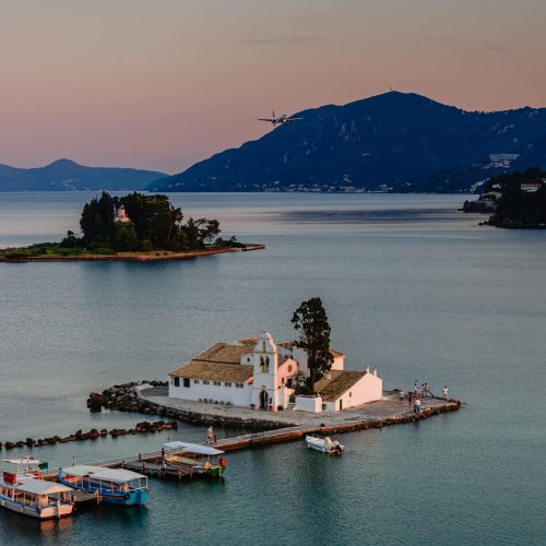 Typical view of Vlacherna Monastery and Mouse island with airplane landing, Corfu, Greece.